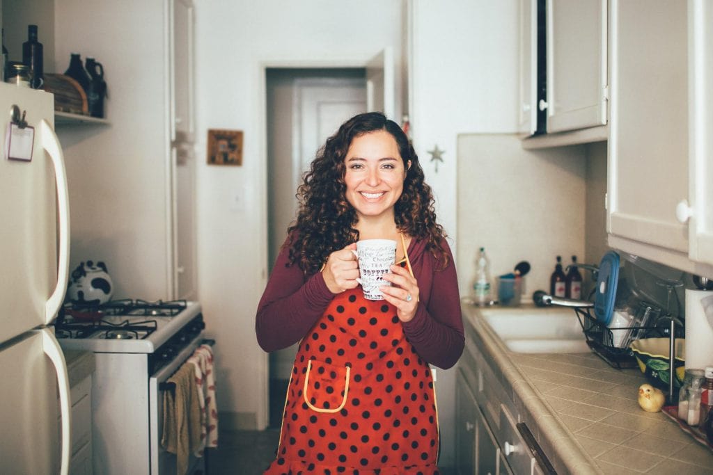 A picture of Maggie Unzueta in her kitchen holding a coffee cup.