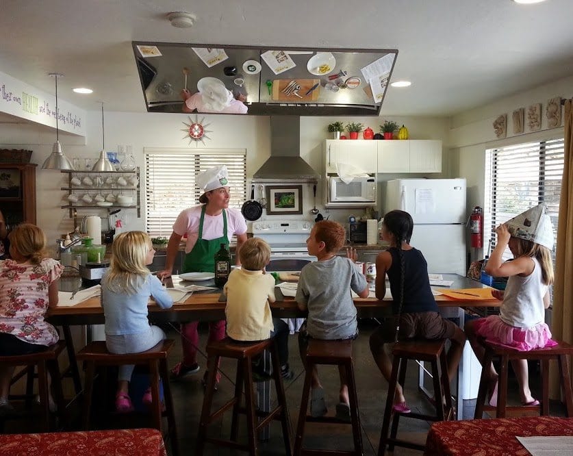 Kids at a cooking class being taught by a chef.