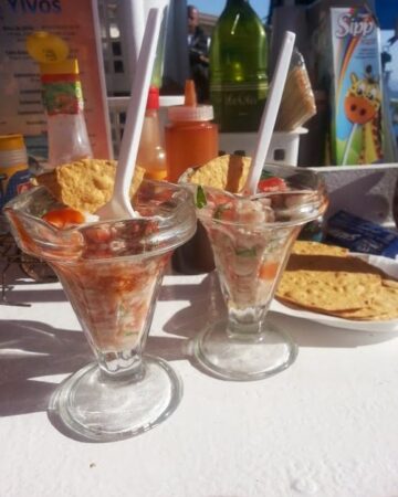 Two glass cups filled with ceviche next to tostadas.