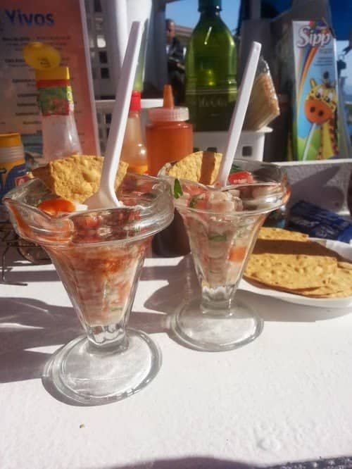 Two glass cups filled with ceviche next to tostadas.