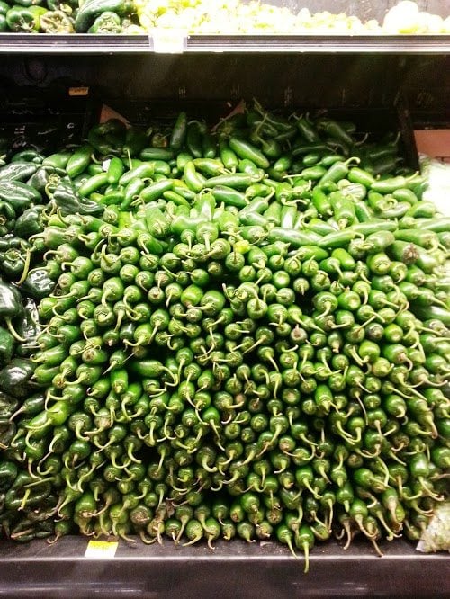 A stack of jalapenos on display at a grocery store.