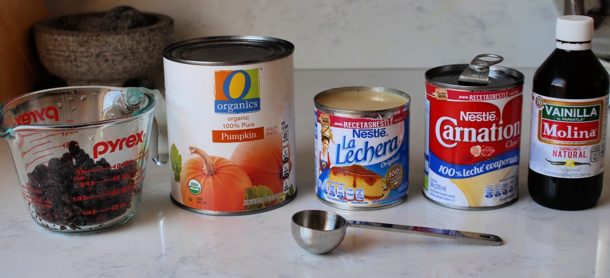 Ingredients for Pumpkin Arroz con Leche and a measuring spoon on a white surface. 