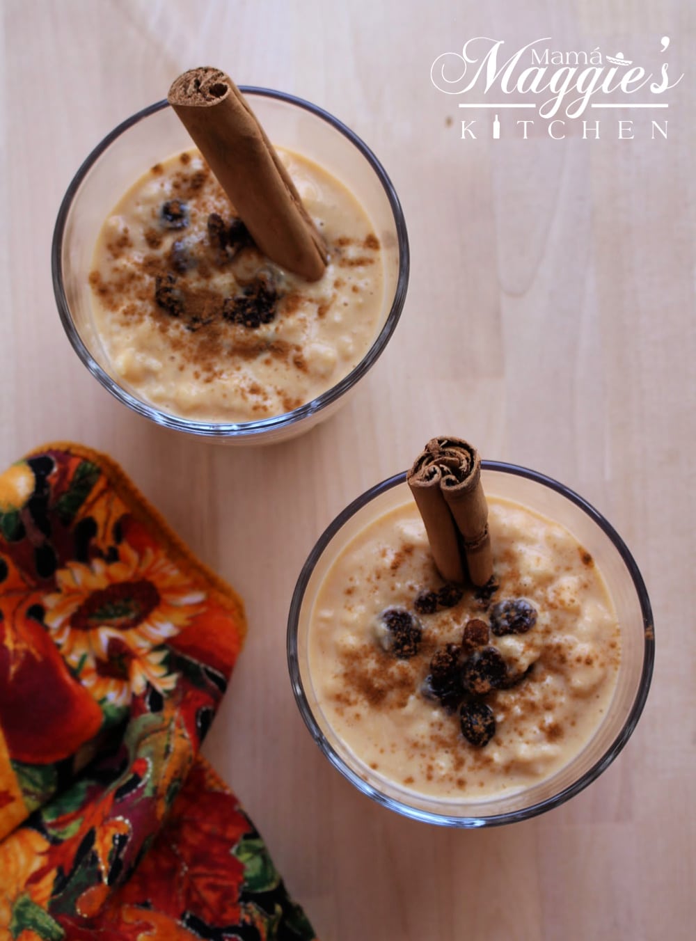 Two cups filled with Pumpkin Arroz con Leche with an orange napkin. 