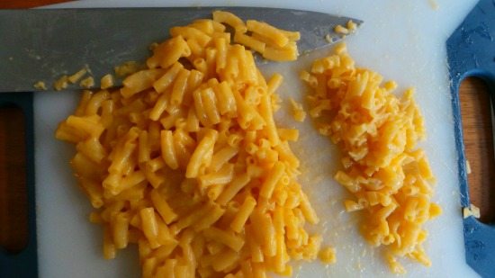 Mac n Cheese on a cutting board and a knife