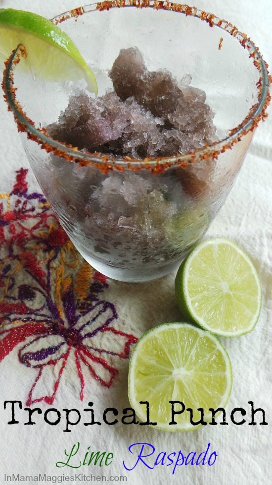 Tropical Punch Lime Raspado in a glass served next to lime wedges.