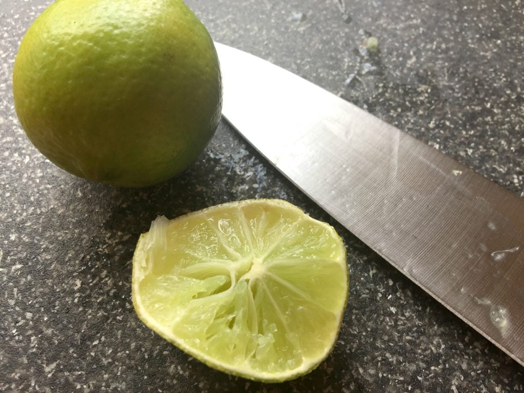 Whole lime and a Lime cut in half with knife 