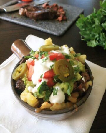 Carne Asada Fries in a container with white napkin slices of beef.