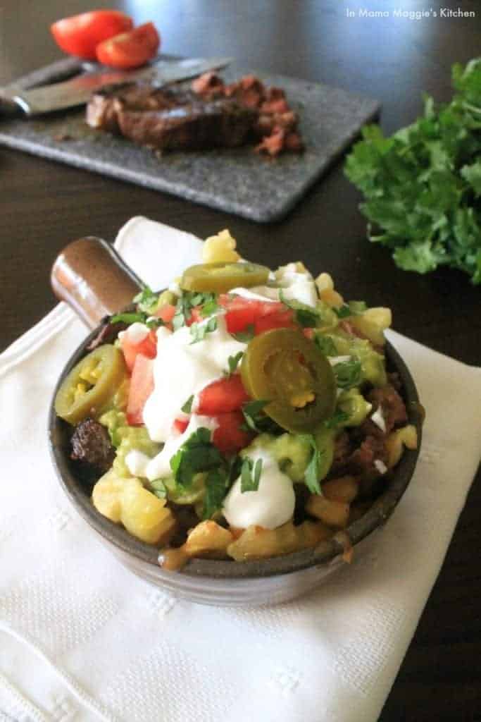 Carne Asada Fries in a container with white napkin slices of beef