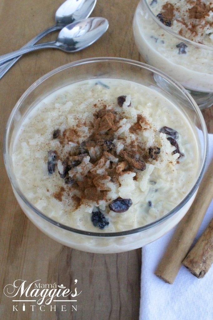 Arroz con Leche in a glass container topped with raisins and sprinkled with ground cinnamon. 