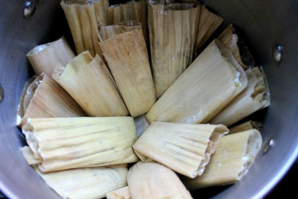 Uncooked tamales placed inside steamer pot.