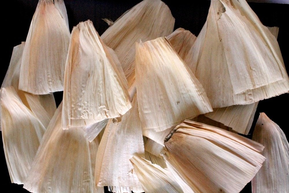 A picture of dried corn husks spread out on a black table.