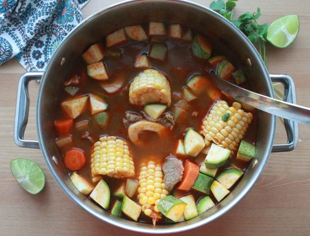 Caldo de Res in a white bowl with large vegetables chunks.