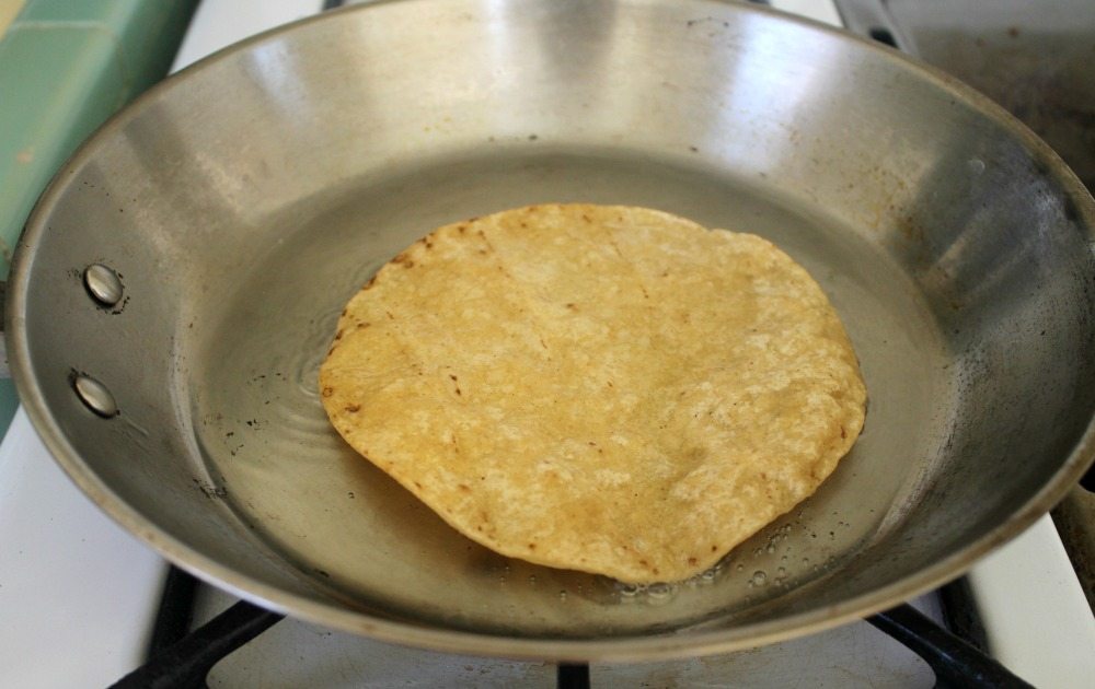Tortilla frying in a metal skillet.