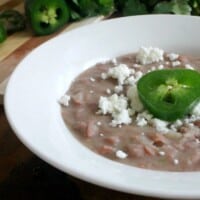 Refried beans topped with slice of jalapeno and crumbled queso fresco.