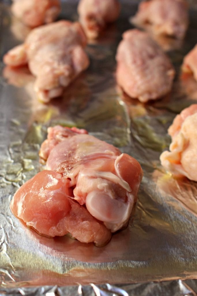 Uncooked chicken wings on a foil-covered baking pan.