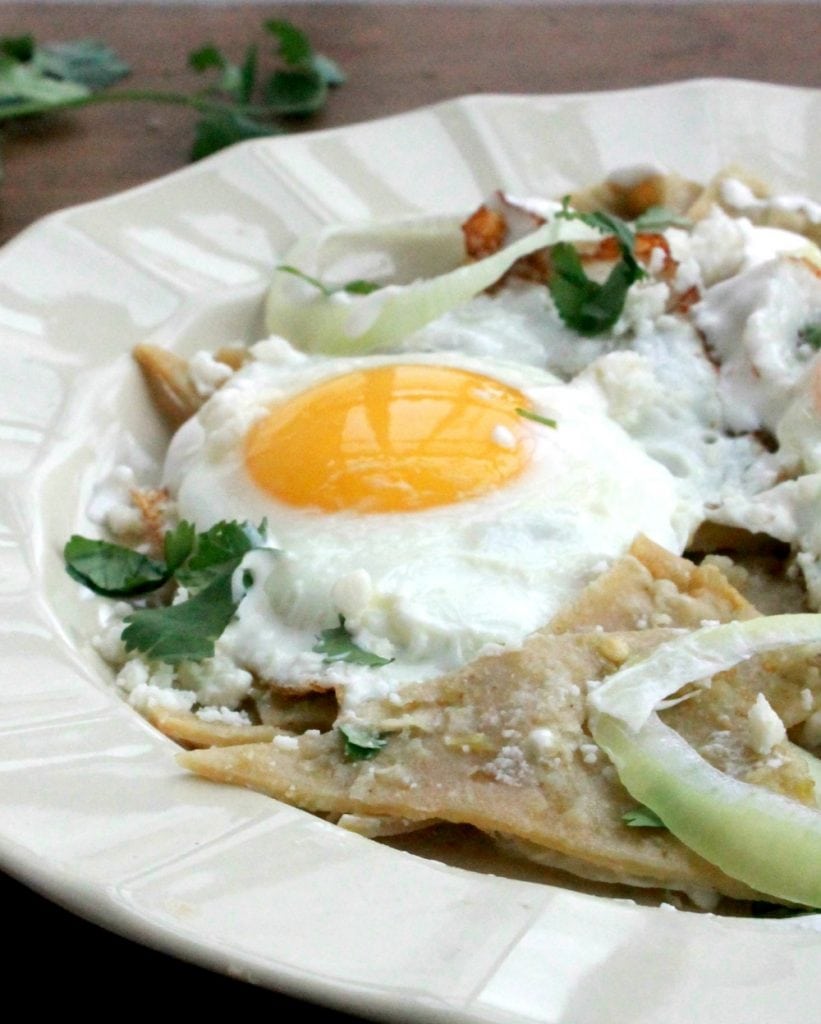 Chilaquiles Verdes served on a plate and topped with a runny egg.