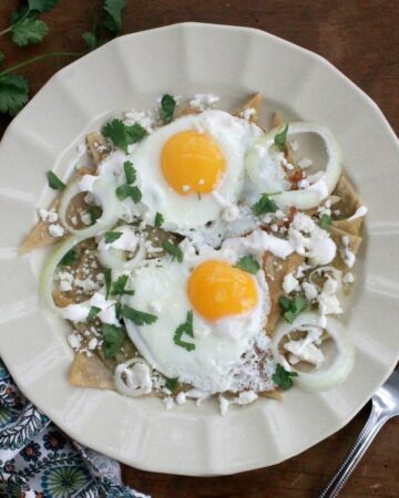 Green Chilaquiles served on a plate and topped with two runny eggs.