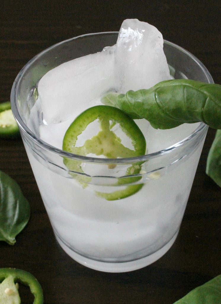 Jalapeño Basil Margarita in a glass with ice, jalapeno slices, and basil leaves.