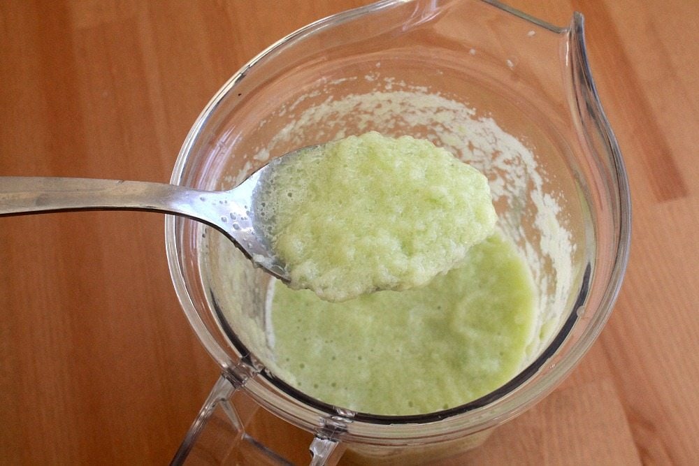Spoon showing the blended cucumber mixture over the blender.