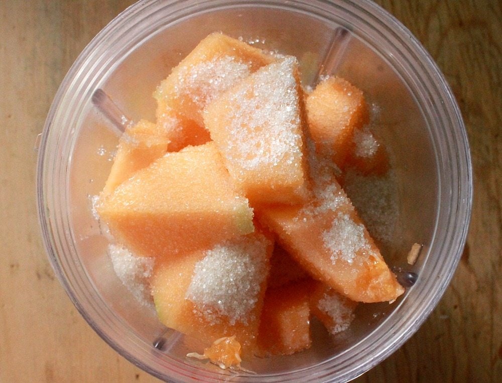 Diced cantaloupe in a blender with sugar.