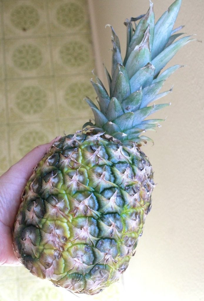 Hand holding a pineapple.