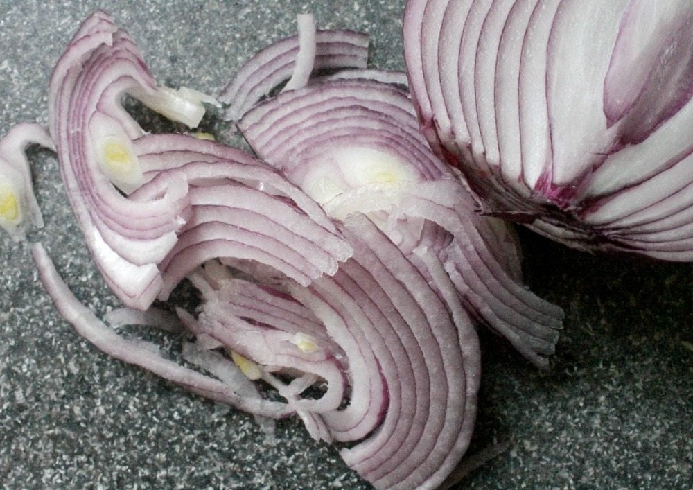 Slices of red onion on a cutting board.