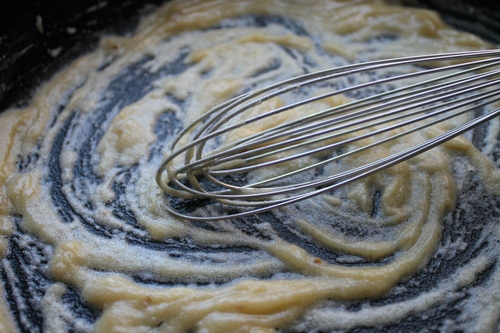 A whisk in a skillet with butter and flourl