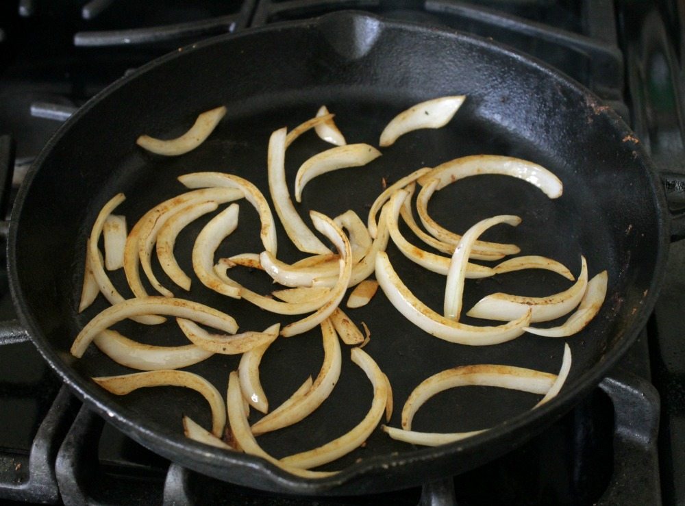 Onions cooking in a cast iron skillet.