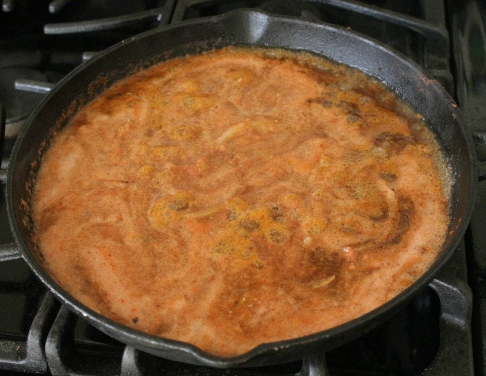 Red salsa cooking in a cast iron skillet.