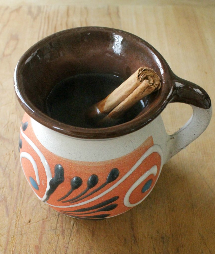 Café de la Olla in a decorative Mexican clay mug with a whole cinnamon stick. 