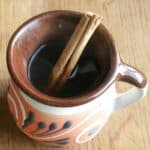 Café de la Olla in a decorative Mexican cup with a cinnamon stick.