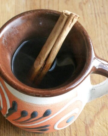 Café de la Olla in a decorative Mexican cup with a cinnamon stick.