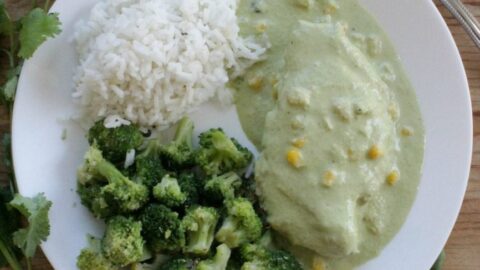 Chicken in Creamy Poblano Sauce on a white plate topped with corn kernels and surrounded by rice and broccoli.