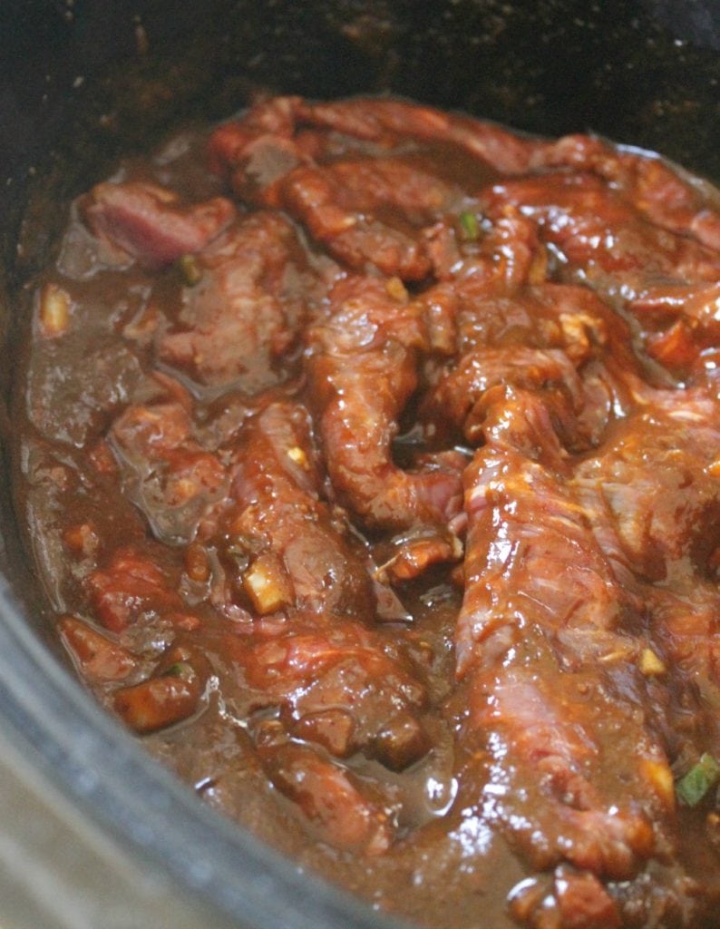 Beef and sauce cooking in a slow cooker.