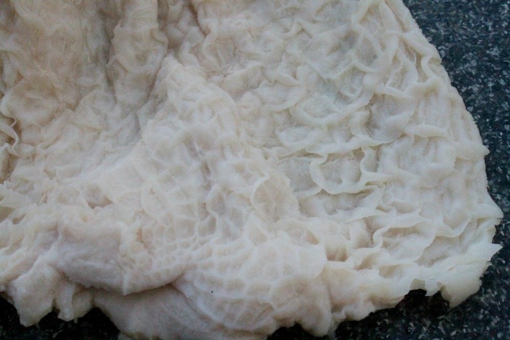 Honeycomb tripe spread out on a cutting board.