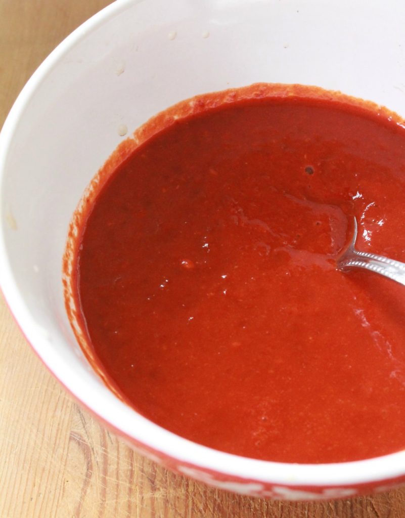 Red chile sauce in a bowl with a spoon. 