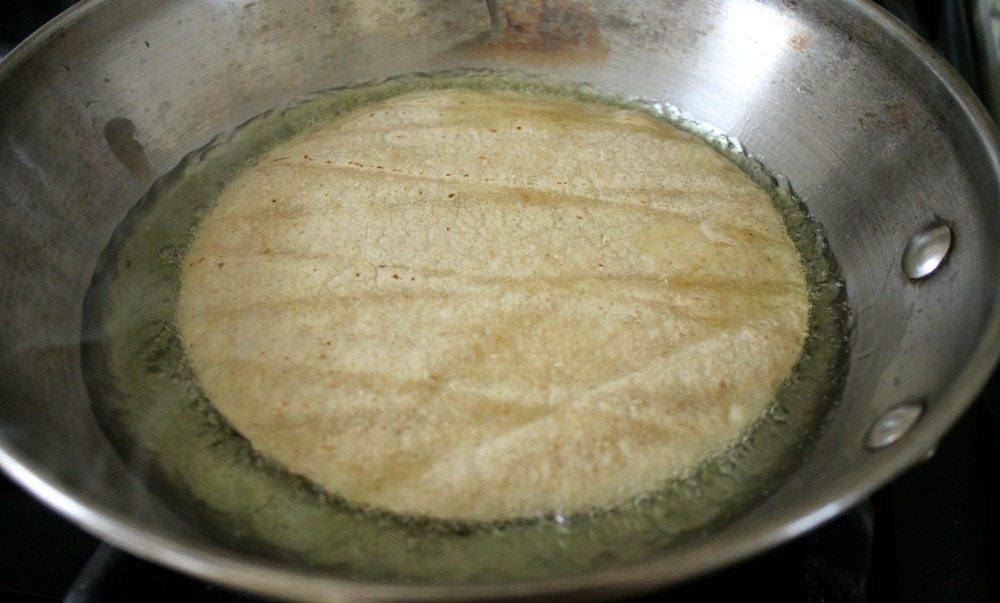 Corn tortilla frying in oil in a pan