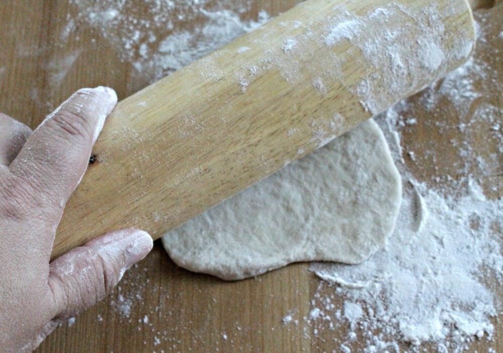 Hand on Rolling Pin that is rolling out the dough