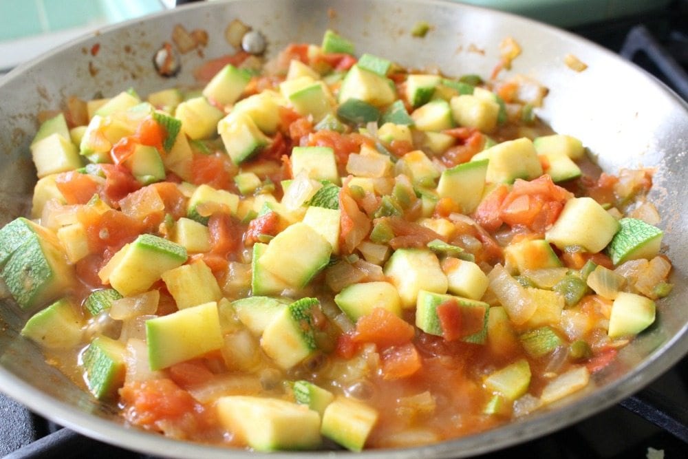 Calabacitas mixed with tomatoes and onions in a skillet