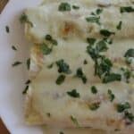 Enchiladas Suizas on a white plate topped with chopped cilantro