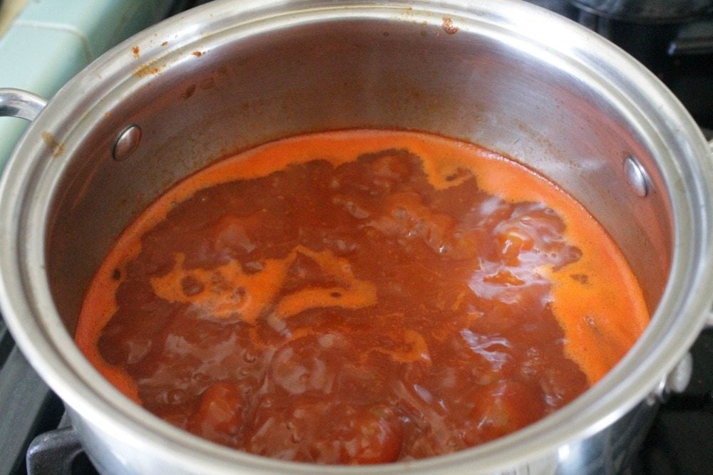 Red guajillo sauce boiling inside a stock pot. 
