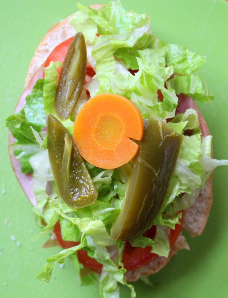 Bread topped with ham, lettuce, tomatoes, and pickled jalapenos and pickled carrots