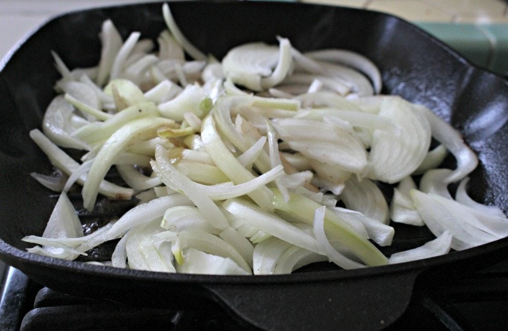 Onion slices cooking in cast iron skillet.