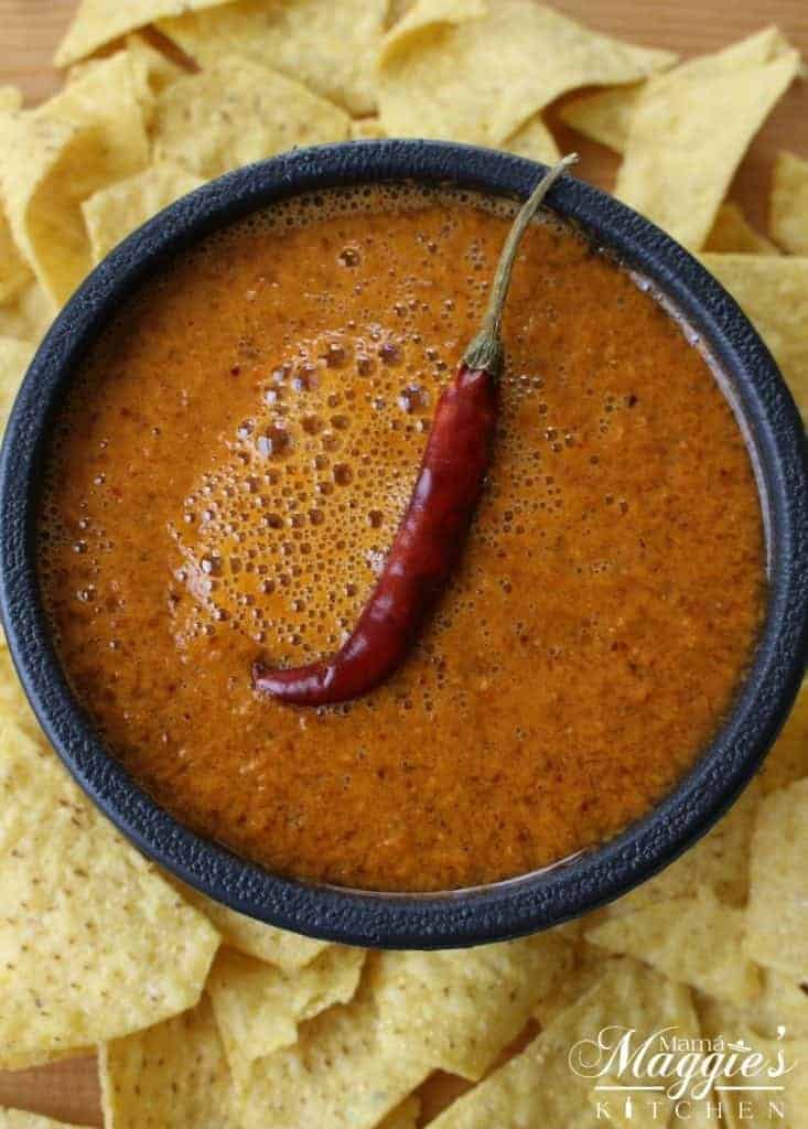 Bowl of Chile de Arbol Salsa surrounded by chips and topped with a single dried chile