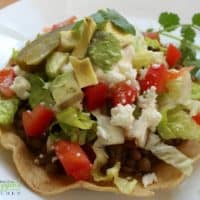 Lentil Tostadas topped with lettuce, tomatoes, avocado, and queso fresco.