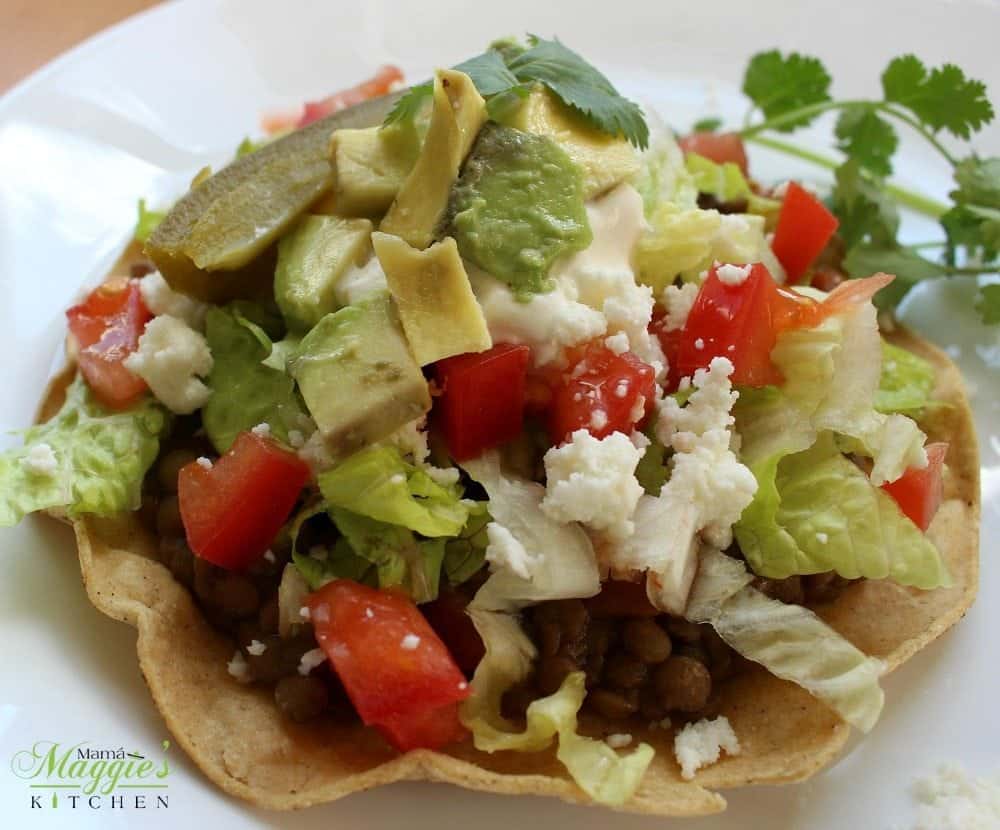 Lentil Tostadas topped with lettuce, tomatoes, avocado, and queso fresco. 