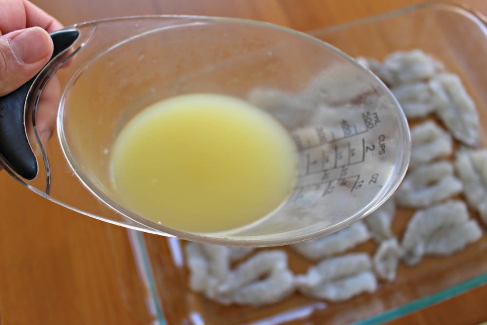 Measuring cup with lime juice over shrimp