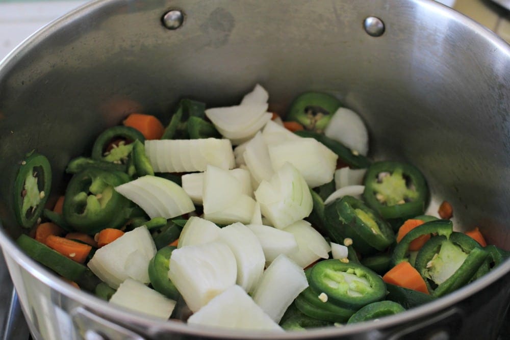 Onions, jalapenos, and carrots cooking in a stockpot.