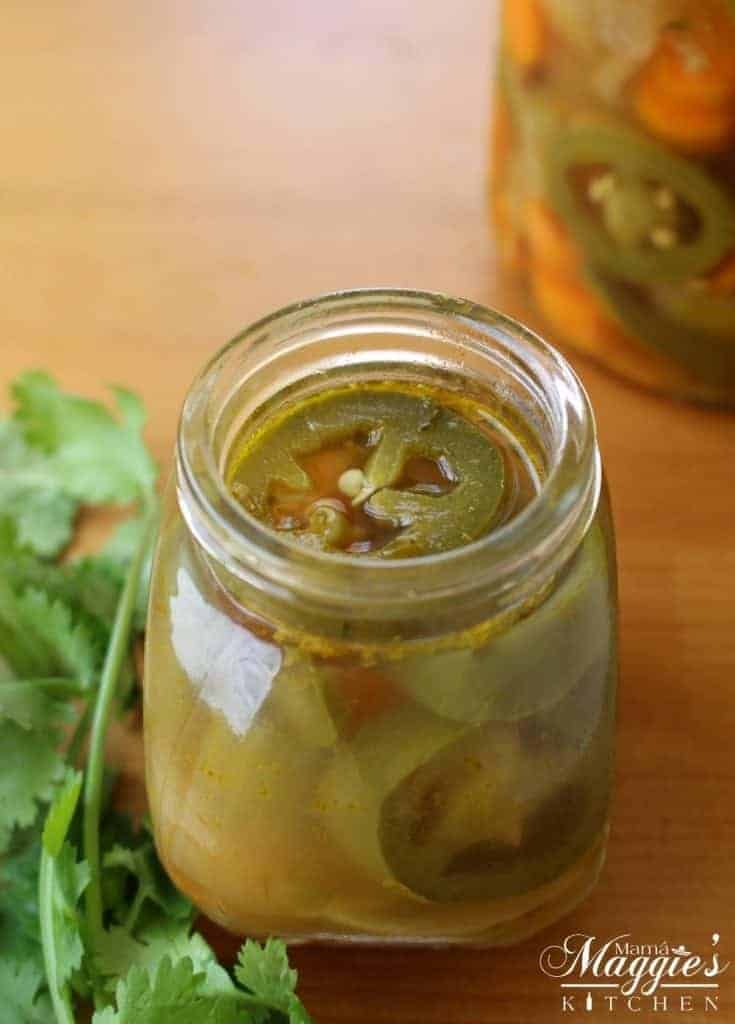 Pickled Jalapenos Chiles en Vinagre surrounded by jar and cilantro. 