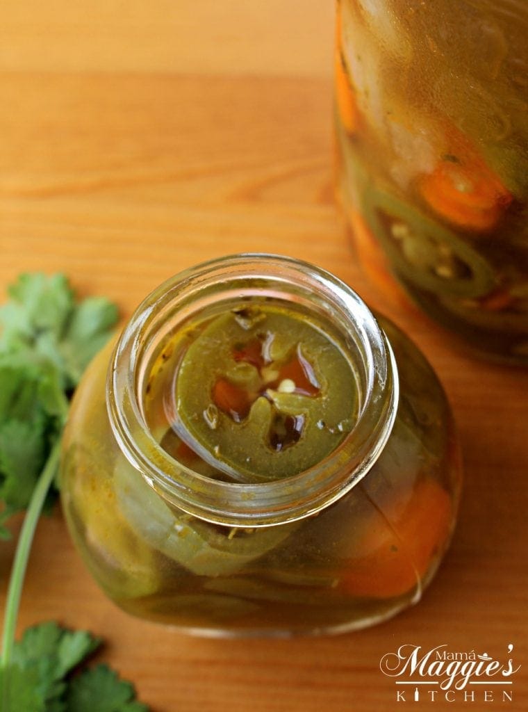 Pickled jalapenos in a jar with cilantro.